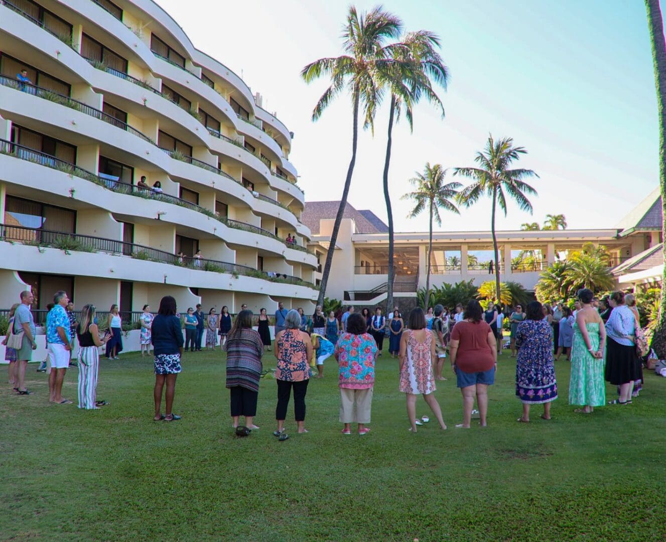 A group of people standing in the grass near some buildings.