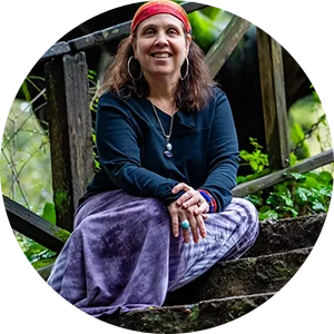 A woman sitting on top of steps in the woods.